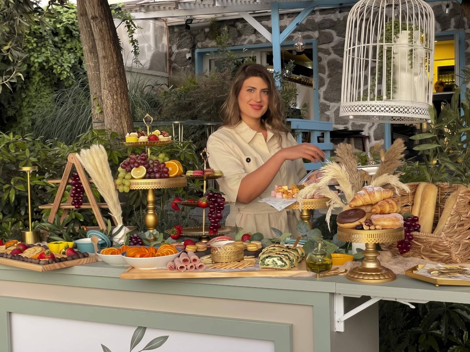 Catalina atendiendo el carro Casa Oliva con charcutería, frutas y bollería en un evento al aire libre
